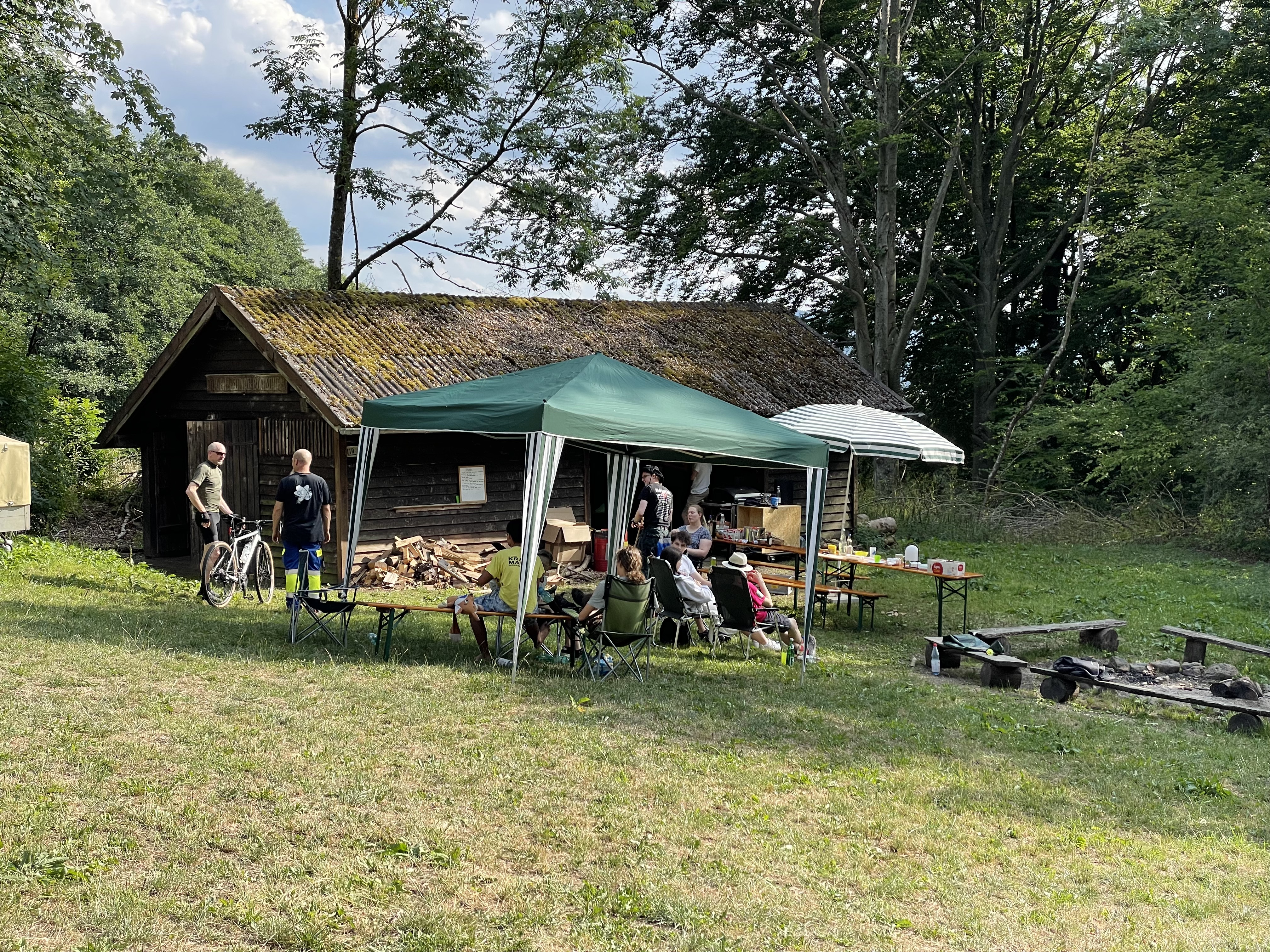 Grillhütte mit Campingausrüstung und Personen